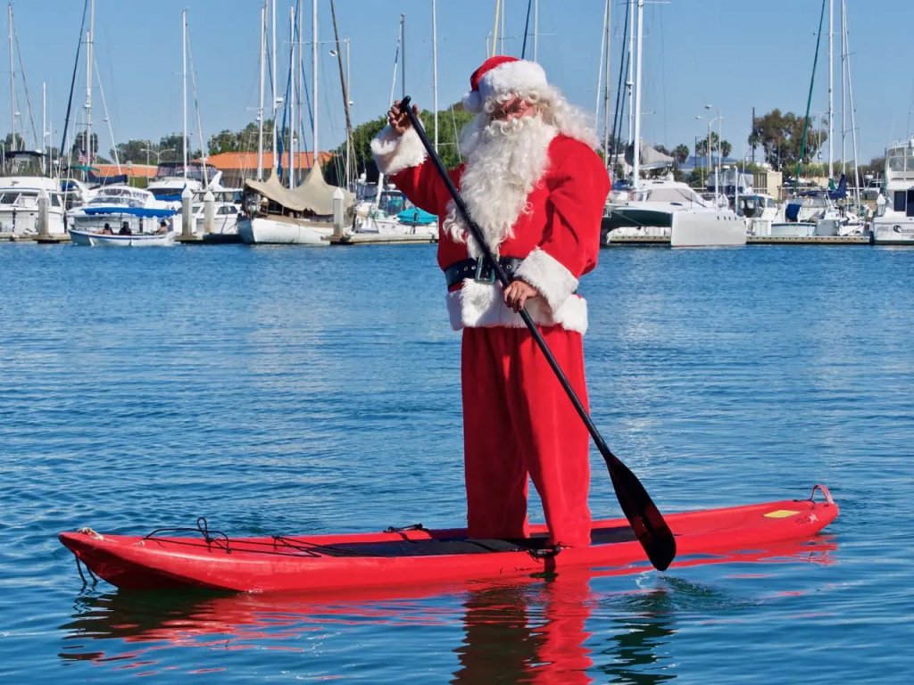 Man dressed as Santa Clause paddling in the Ventura Harbor 