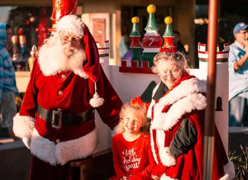 Santa and Ms. Clause standing with young girl in Ventura Harbor Village.