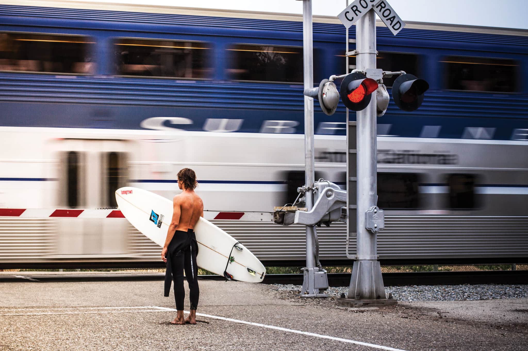 surfer in front of amtrak pacific surfliner train