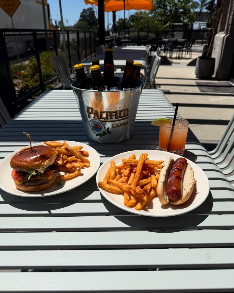 Ventura's Best Sports Bars for Game Day Plate full of burger and fries and another plate full of a hot dog and fries with a margarita and a beer bucket at the varsity club