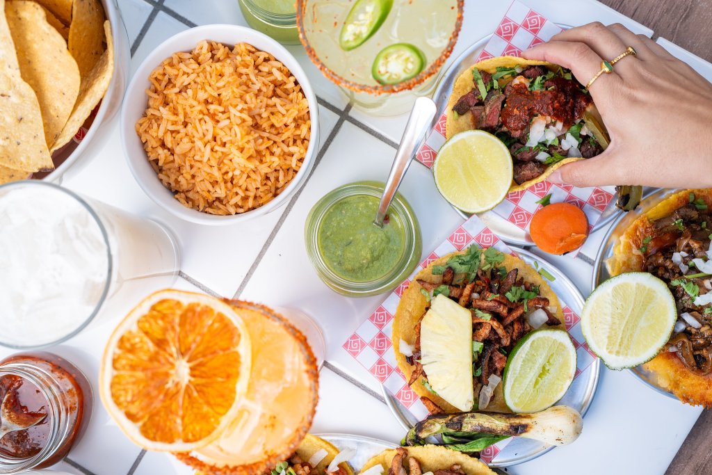 Plates full of tacos and rise and glasses of margaritas