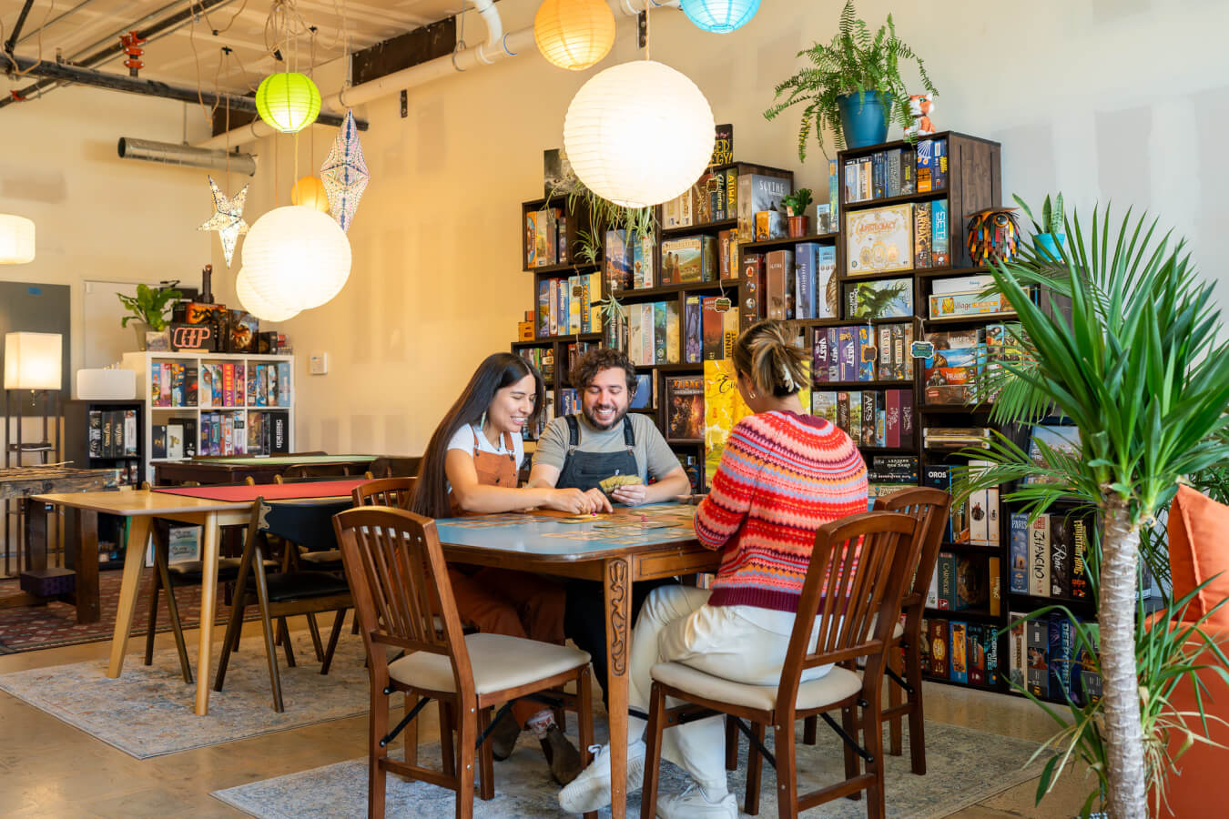 Friends gather at a table playing a board game at Punchboard Cathedral in Ventura, California